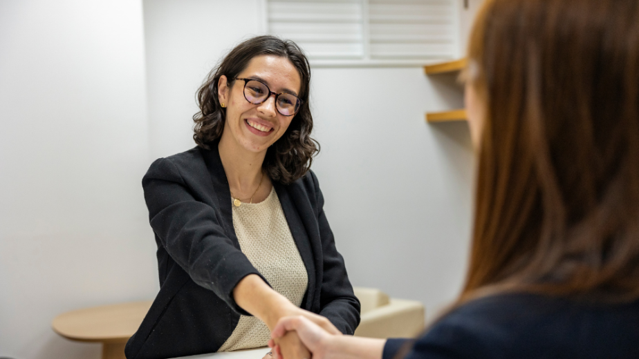 two females shaking hands with one smiling
