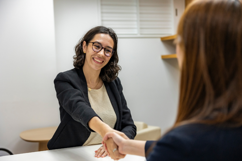 two females shaking hands with one smiling