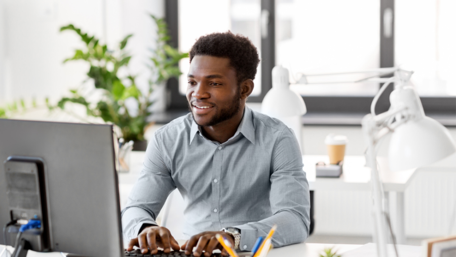 a black professional man working away on his desktop at a desk