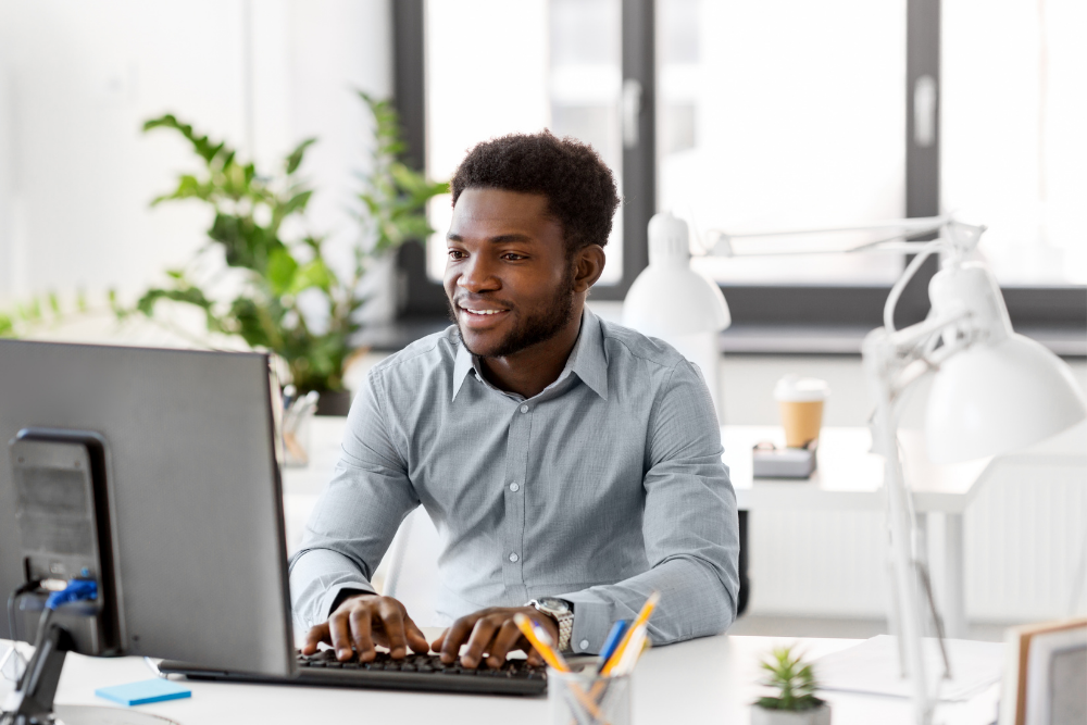 a black professional man working away on his desktop at a desk