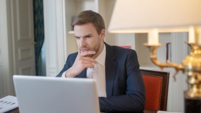 a man waiting and sitting in front of his laptop in a room