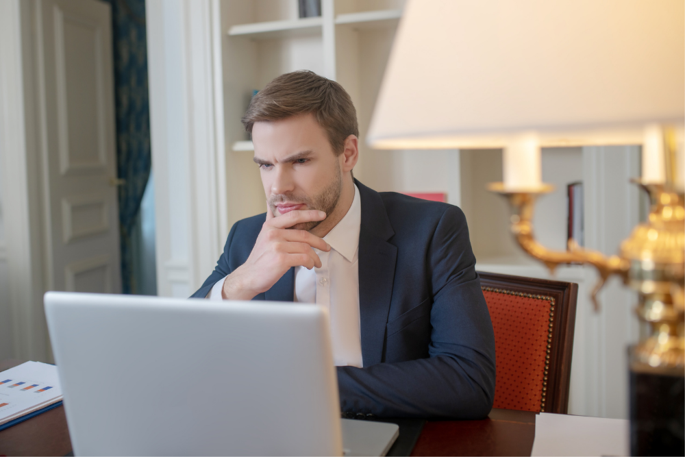 a man waiting and sitting in front of his laptop in a room