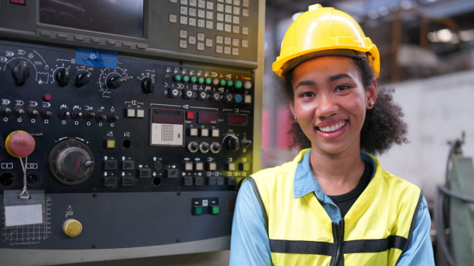 a very young black female industrial worker with her arms crossed smiling