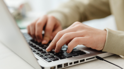a close up of a person typing on their laptop