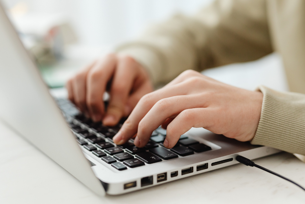 a close up of a person typing on their laptop