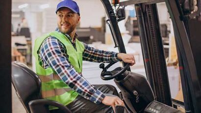 A certified forklift operator driving a forklift in a warehouse
