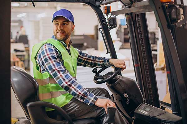 A certified forklift operator driving a forklift in a warehouse