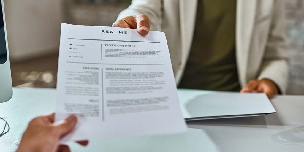 A close up of a printed resume on a desk before it is screened
